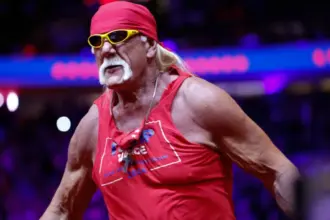 Hulk Hogan posing in red and yellow wrestling attire during a WWE match.