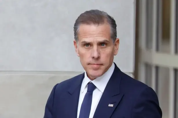 Portrait of Hunter Biden in a suit, standing thoughtfully with a neutral background.